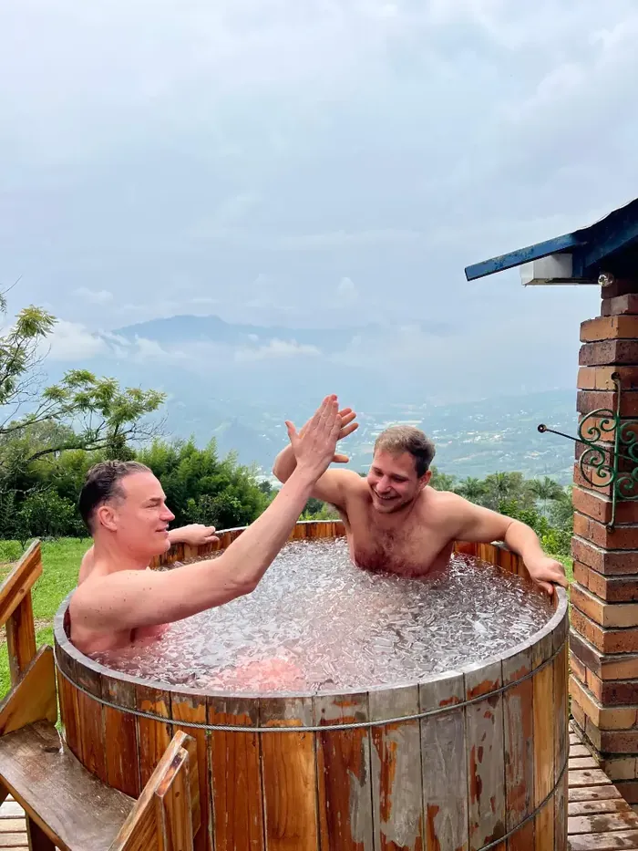 Harmonica Ayahuasca Retreat Colombia Ice bath high five Two men high-fiving in the ice bath