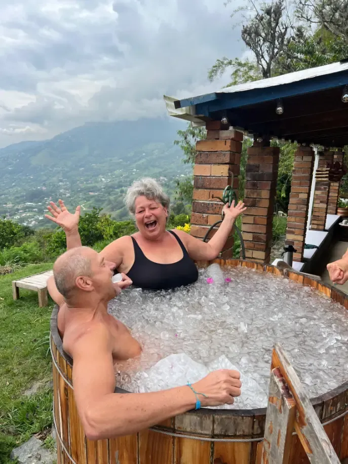 Harmonica Ayahuasca Retreat Colombia Ice bath laughter Two participants laughing in the ice bath with the mountains behind