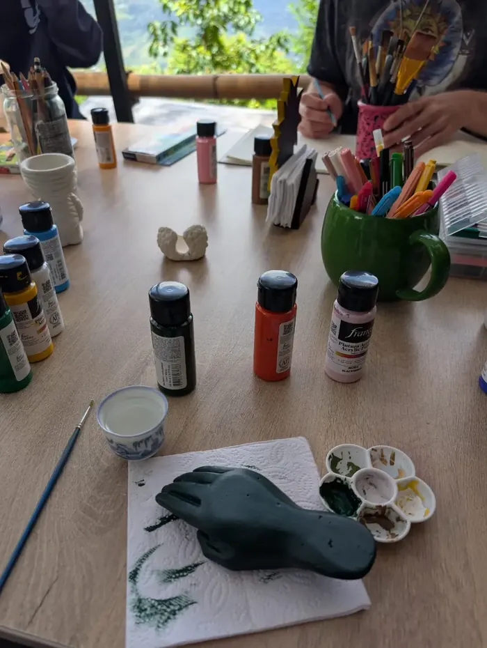 Harmonica Ayahuasca Retreat Colombia Painting a clay figure Paints, brushes and a clay figure on the table during an art session