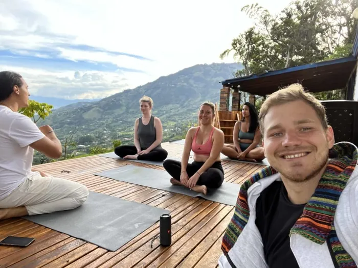 Harmonica Ayahuasca Retreat Colombia Yoga on the deck Participants doing yoga on the wooden deck with the mountains behind